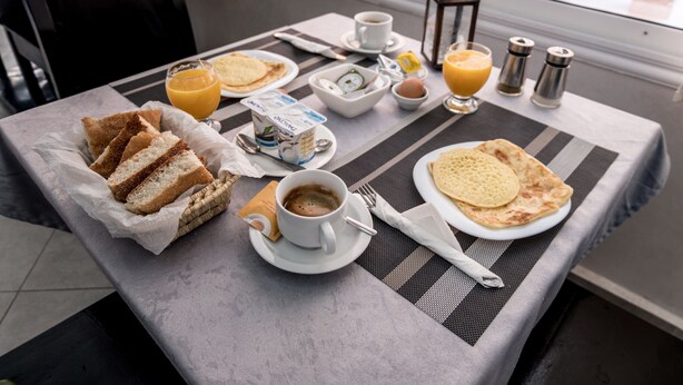 Une table de petit-déjeuner avec du pain, du café, du jus d’orange et une lanterne.