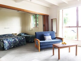 Una habitación con un sofá azul, una mesa de madera con fruta y una cama con ropa de cama floral.