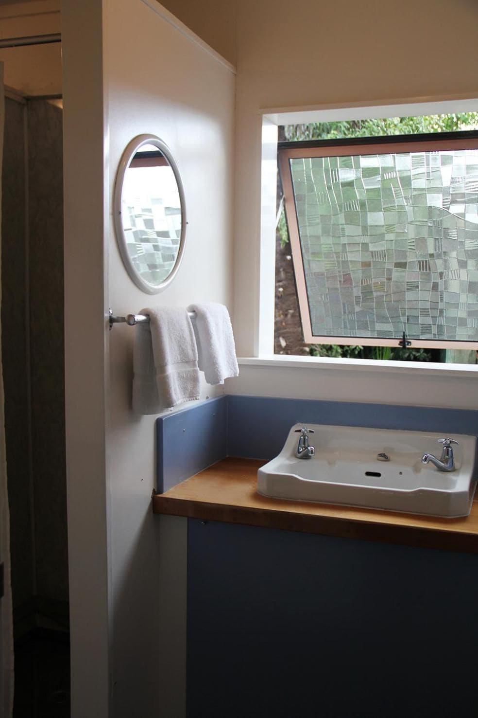 Een badkamer met een raam, een wastafel en een handdoekhouder.