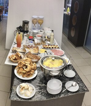A buffet table with various food items, including pastries, bread, and a hot pot. - Rio Grande Apart (Rosario)