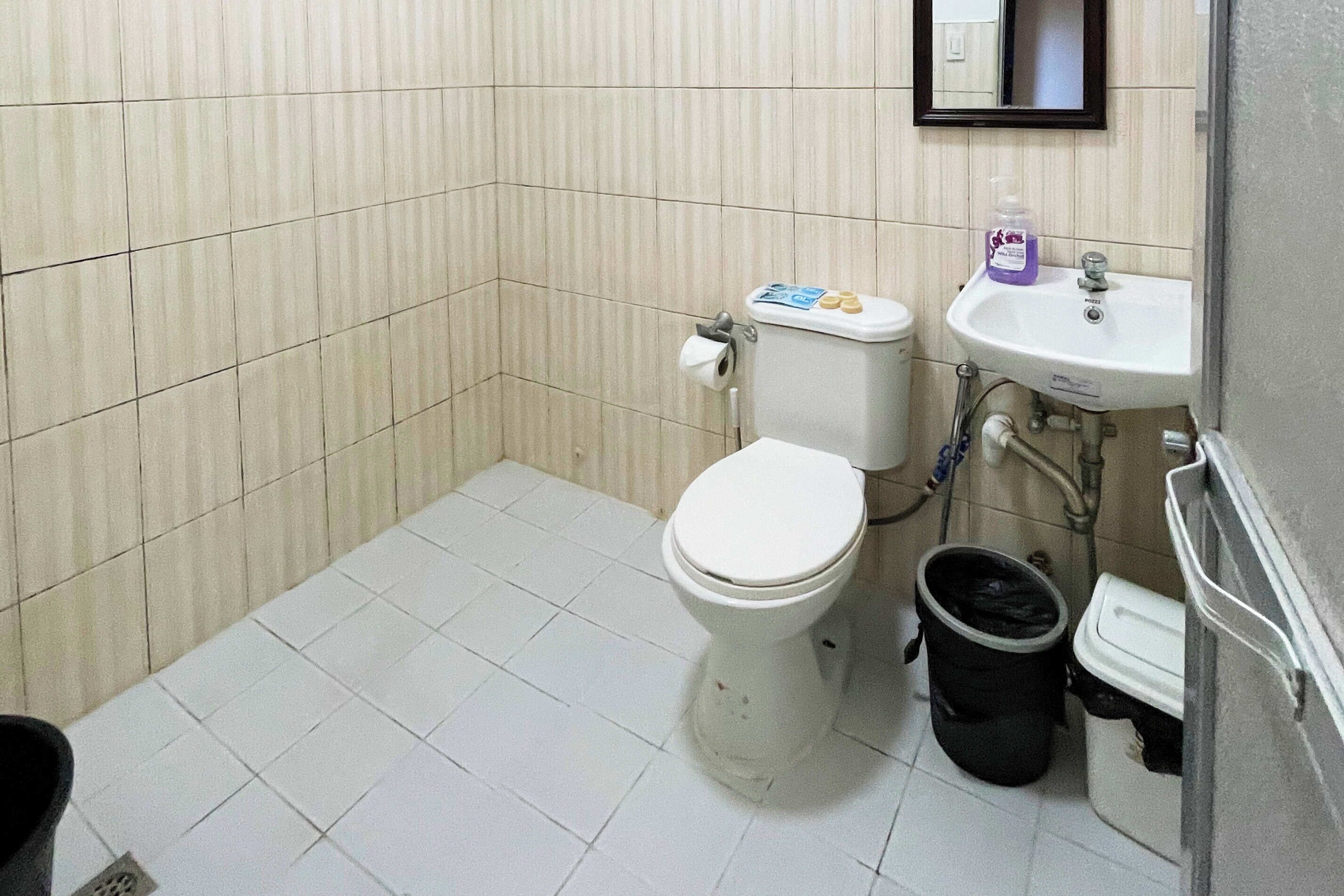 Une petite salle de bain avec des toilettes, un lavabo et une poubelle.