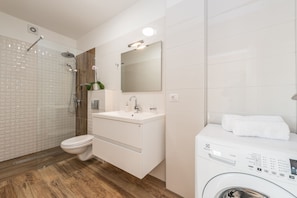 Un baño moderno con ducha, inodoro, lavamanos y lavadora.
