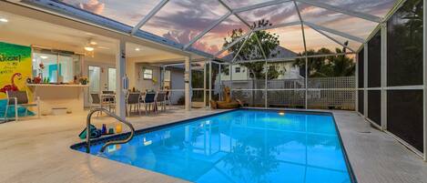 A swimming pool with a glass ceiling, surrounded by lounge chairs and a poolside bar.