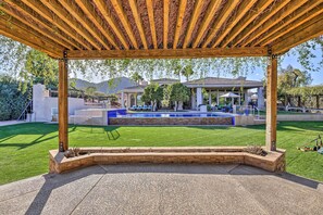 A covered patio with a pool, a well-maintained lawn, and a view of a house with a patio and a pergola. - Lavish Paradise Valley Home w/ Sports Court & Pool (Paradise Valley)