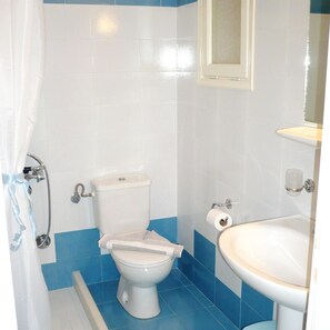 A bathroom with a toilet, a shower, and a sink. - Filoxenia (Amorgos)