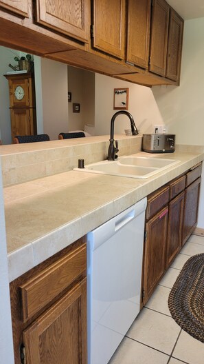 A kitchen with wooden cabinets, a double sink, and a dishwasher.