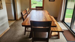 A dining area with a large wooden table, four chairs, a chandelier, and a view of the outdoors through a large window. - Snowcreek Resort Vacation Rental 267 (Mammoth Lakes)