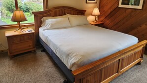A wooden bed with white linens in a room with a window, a nightstand, and a picture on the wall. - Snowcreek Resort Vacation Rental 267 (Mammoth Lakes)