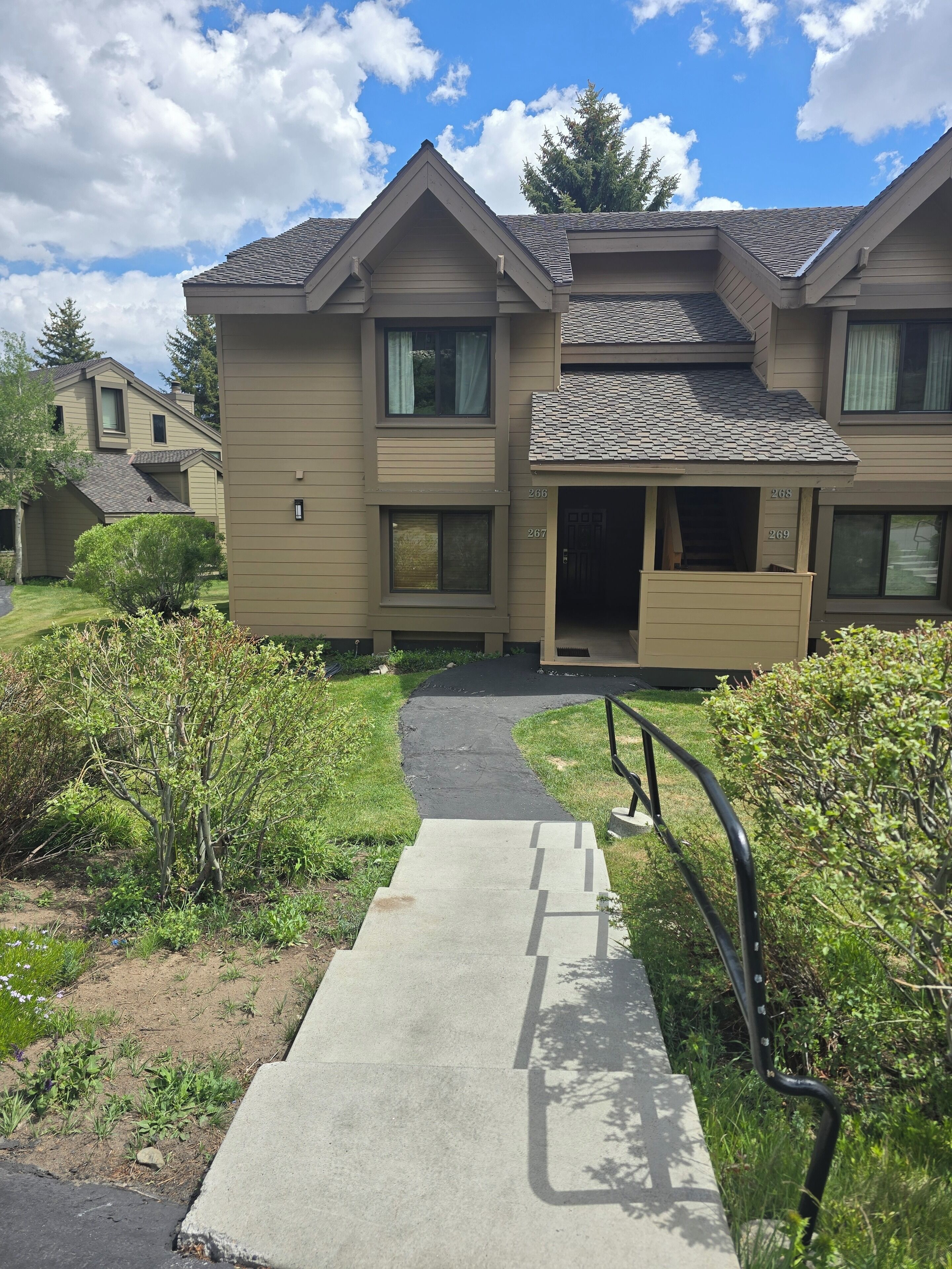 A multi-story residential building with a covered entrance, a paved driveway, and a well-maintained lawn.