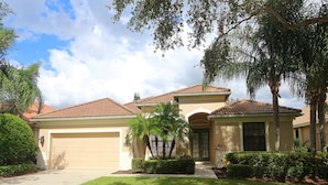 A two-story house with a garage, a well-maintained lawn, and mature trees. - Tailfeather Home on Golf Course by RVA: Stylish 4BR w Pool & Close to Beach (Bradenton)