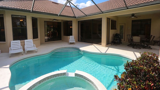 A swimming pool with a glass ceiling, surrounded by lounge chairs and a patio area. - Tailfeather Home on Golf Course by RVA: Stylish 4BR w Pool & Close to Beach (Bradenton)