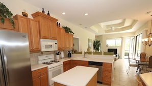 A modern kitchen with wooden cabinets, stainless steel appliances, and a central island. - Tailfeather Home on Golf Course by RVA: Stylish 4BR w Pool & Close to Beach (Bradenton)