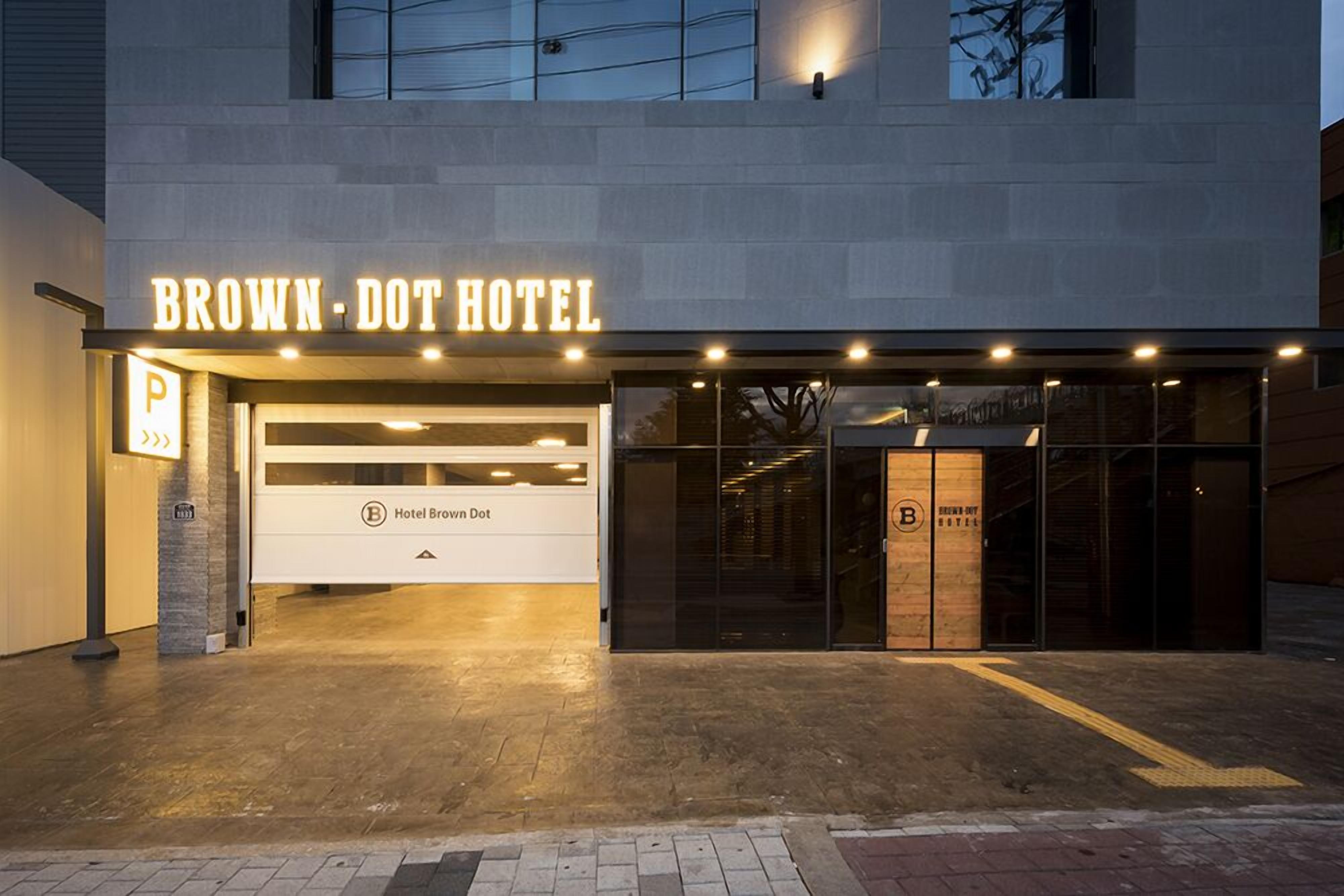 The exterior of the Brown-Dot Hotel with a modern design, a prominent illuminated sign, and a clear entrance.