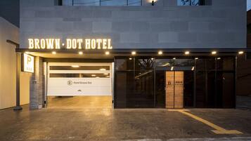 The exterior of the Brown-Dot Hotel with a modern design, a prominent illuminated sign, and a clear entrance.