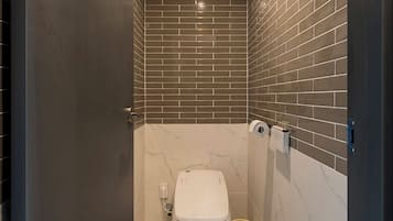 Une petite salle de bain comprenant des toilettes, une poubelle et un distributeur de serviettes.