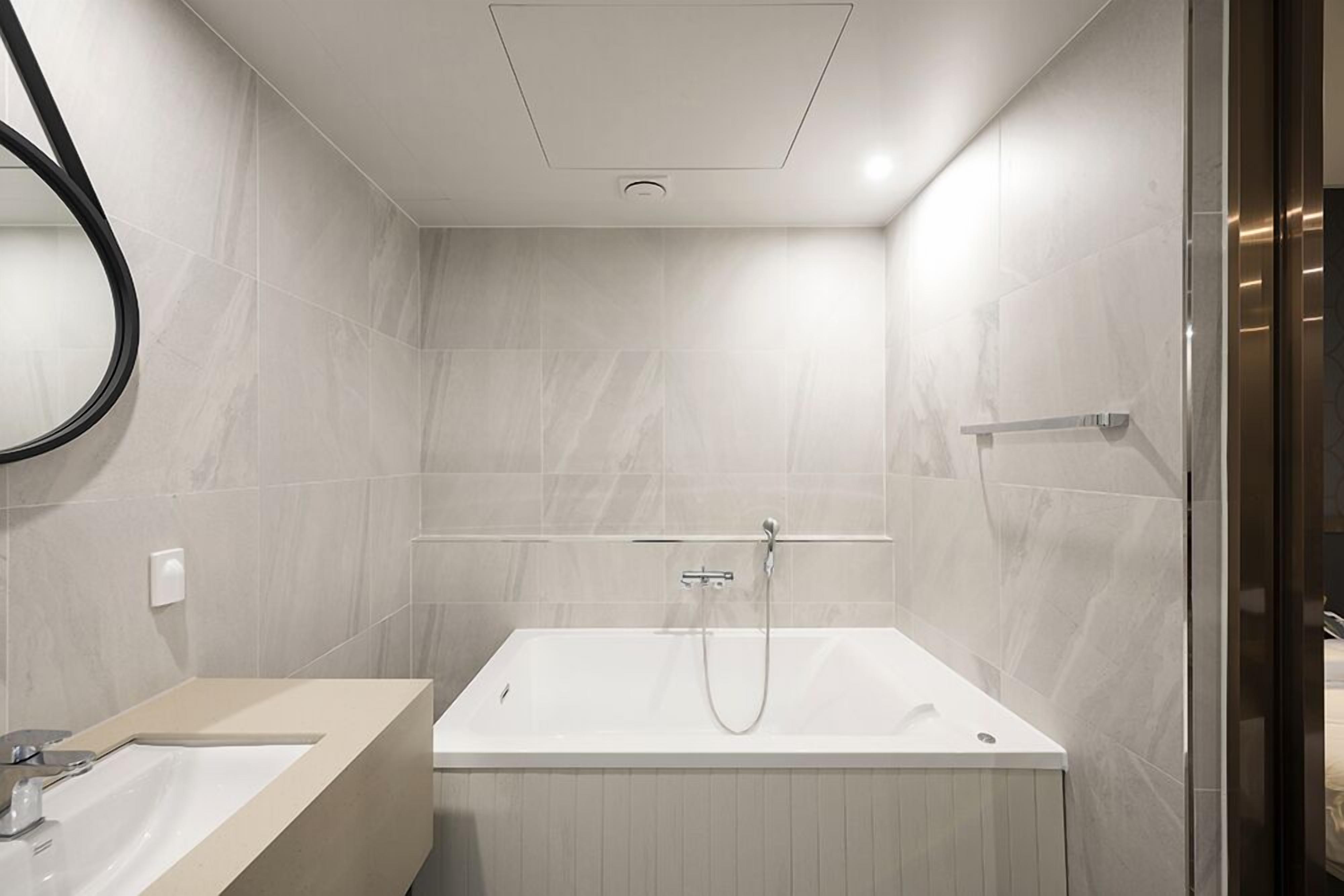 A modern bathroom with a bathtub, a sink, and a mirror.
