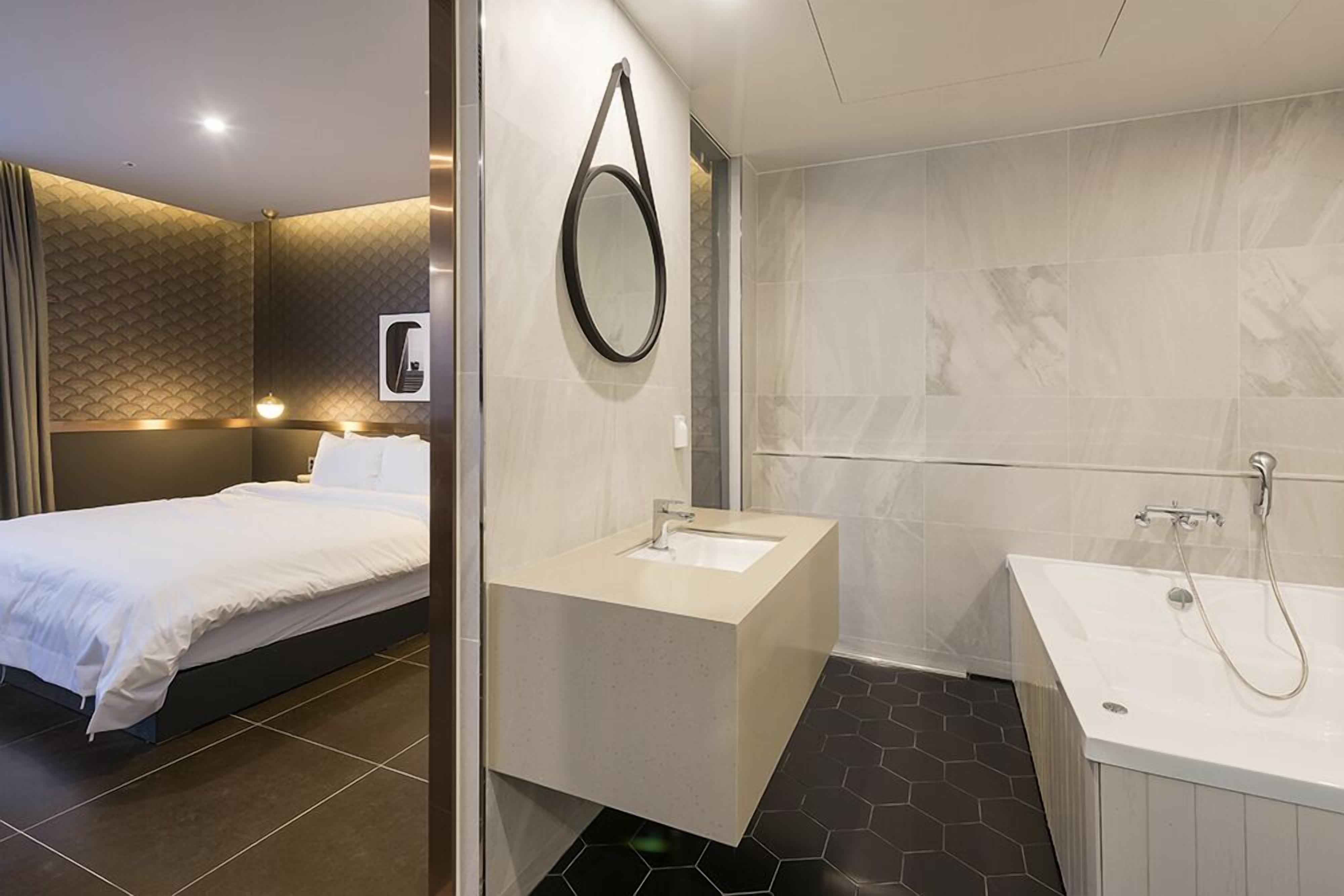 Een moderne hotelkamer met een bed, een badkamer met een badkuip en een wastafel.