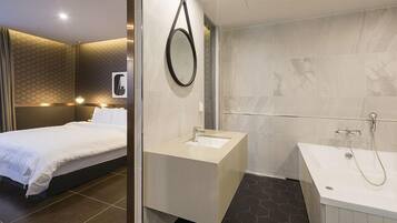 Een moderne hotelkamer met een bed, een badkamer met een badkuip en een wastafel.