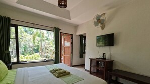 Un cuarto de hotel con una cama grande, un televisor en la pared y vistas al exterior a través de la ventana.