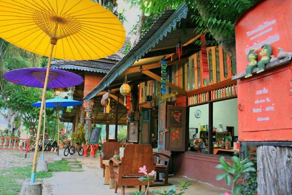 An outdoor seating area with wooden furniture and umbrellas. - Baanmai Kon Muang (Pai)