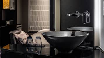 Un bagno moderno con un lavandino nero capiente, uno specchio e un porta asciugamani.