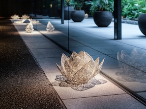 A series of decorative lotus-shaped sculptures on a tiled floor, with potted plants in the background.