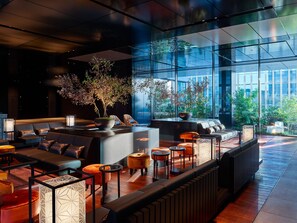 A modern lounge area with seating, a coffee table, and a large window offering a view of the outdoors.