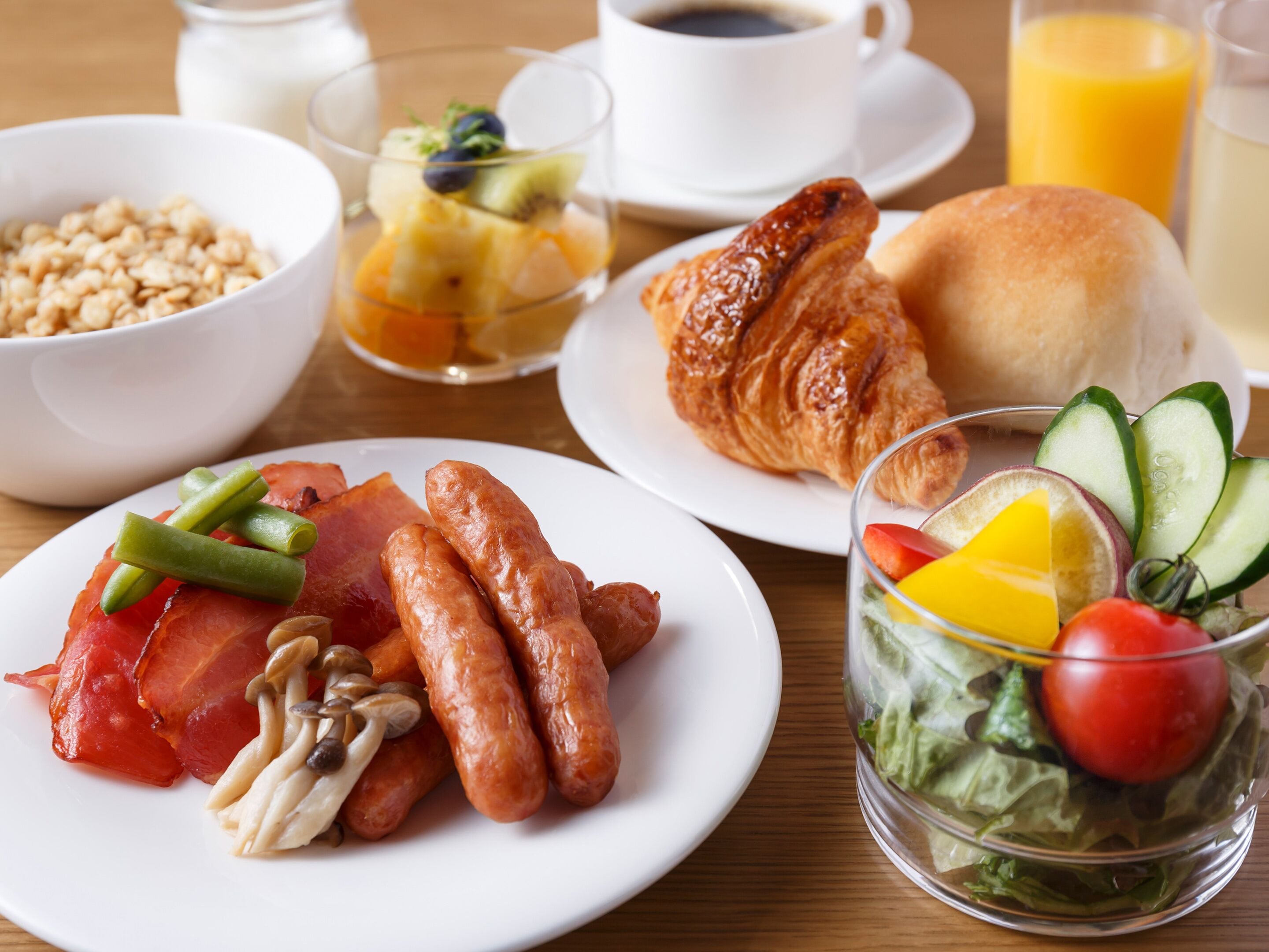 A breakfast setting with plates of food, a glass of juice, and a cup of coffee.