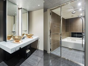 Een moderne badkamer met een douchecabine van glas, een grote spiegel en twee wastafels met decoratieve kommen.