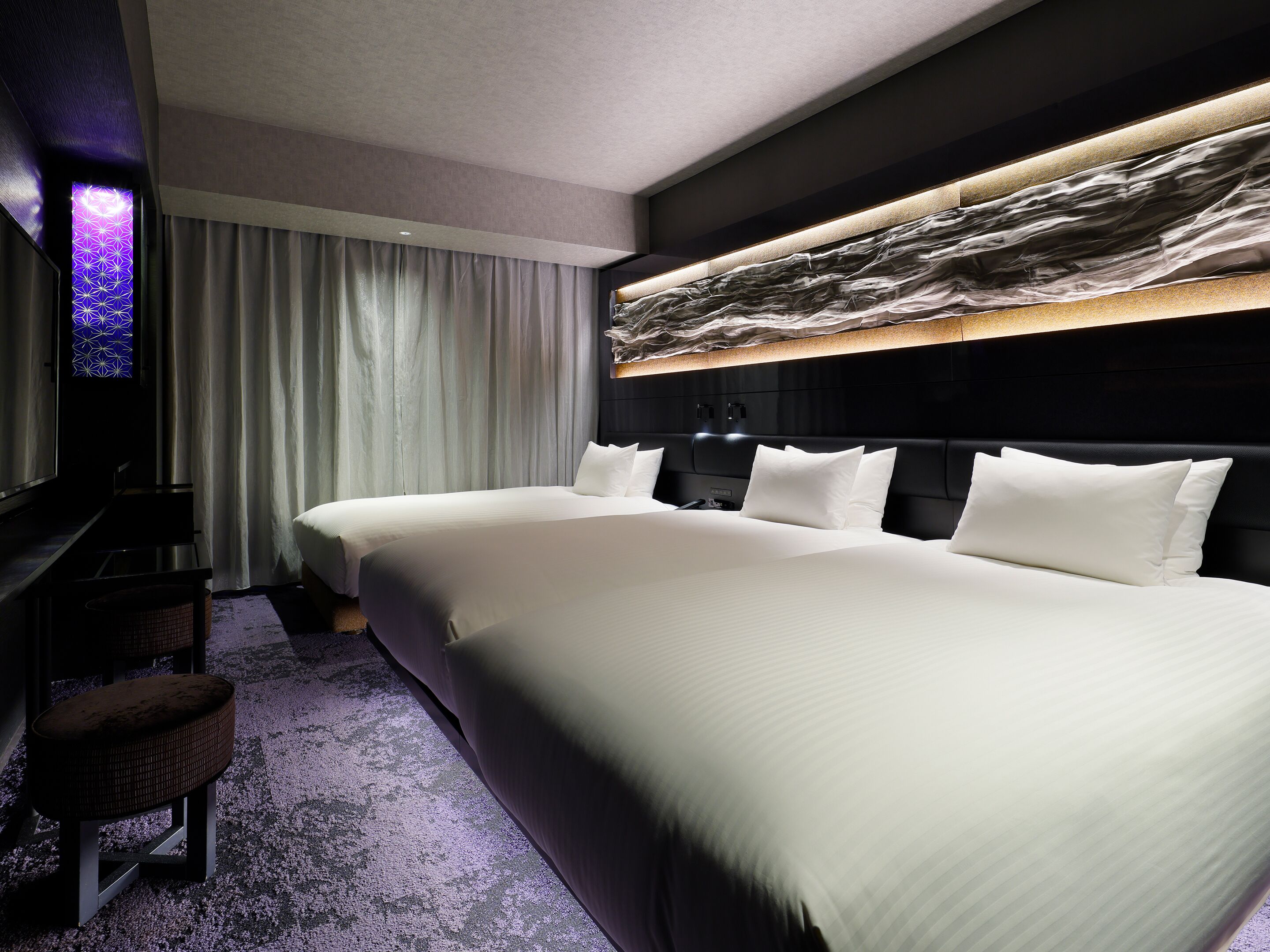 A hotel room with a large bed, a flat-screen TV, and a wall-mounted artwork.