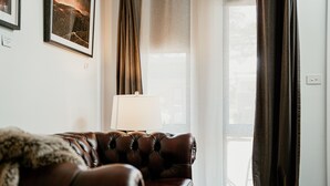 Un sofá de cuero marrón con un cubrecolcha de piel, una lámpara y una ventana con cortinas.