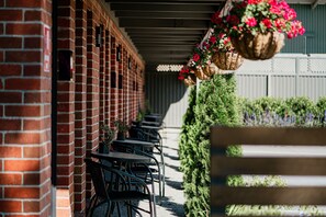 Un edificio de ladrillo con mesas al aire libre y cestas de flores colgantes.