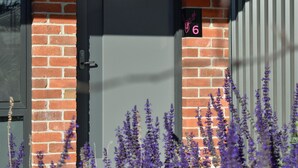 Edificio de ladrillo con puerta gris y un letrero con el número 6.