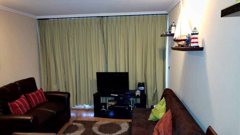 A living room with a dark brown sofa, a lighter brown sofa, a flat-screen TV, and a small table with decorative items.