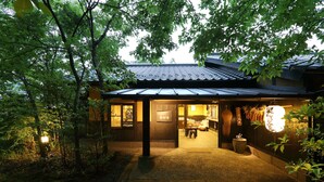 Ett traditionellt japanskt hus med ett tak täckt av tegelpannor, en träfasad och en väl upplyst entré.