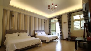 A hotel room with two beds, a chandelier, a window with curtains, and a desk with a chair. - Norman's B&B (Hualien City)