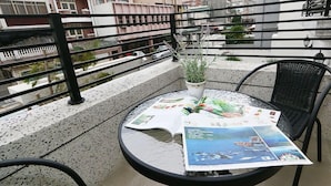 A round table with a magazine on it, a potted plant, and a chair on a balcony with a railing. - Norman's B&B (Hualien City)