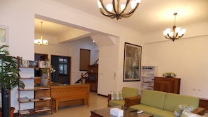 A spacious living room with a green sofa, a wooden coffee table, and a bookshelf. - Norman's B&B (Hualien City)