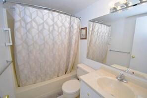 A bathroom with a shower curtain, toilet, sink, and mirror. - Towers 201-Oceanfront 29th St, Pool, Elev, W/D, AC, WIFI (Ocean City)