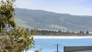 Un paisaje costero con una playa, colinas y una línea eléctrica en primer plano.