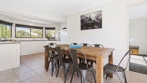 Una cocina moderna con armarios blancos, una mesa de comedor de madera y seis sillas.