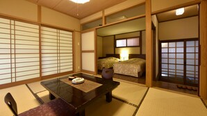 Una habitación japonesa tradicional con suelo de tatami, una mesa baja con posavasos, una silla y una cama con mesita de noche.