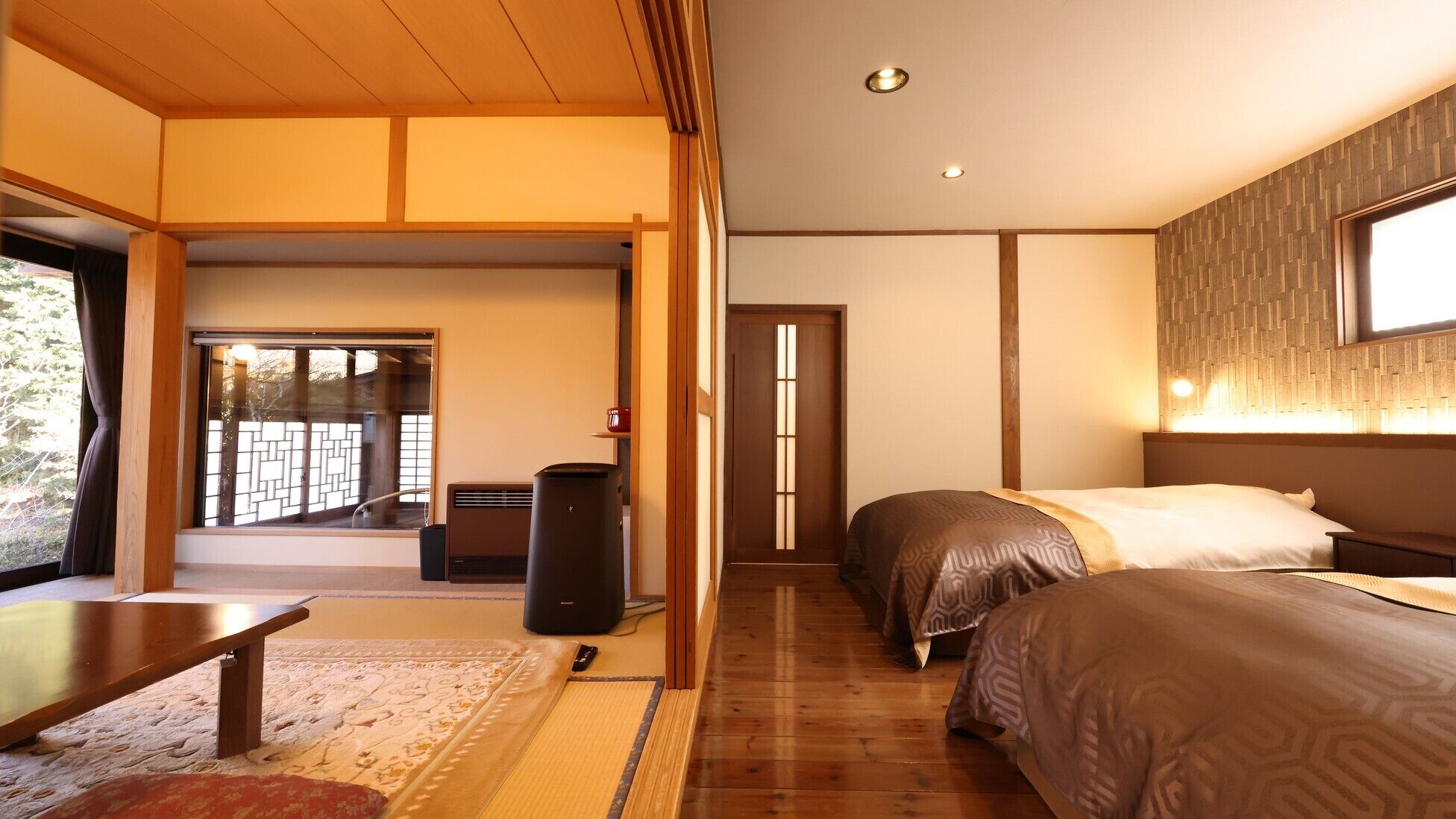 A hotel room with a traditional Japanese interior, including tatami flooring, a sliding door, and a bed with a patterned bedspread.