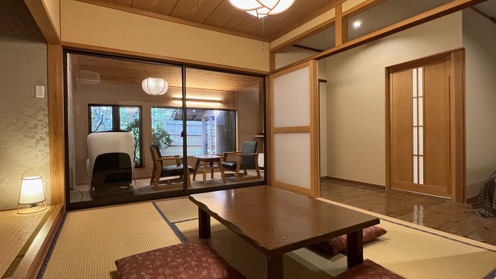 A traditional Japanese room with tatami flooring, a low table, and sliding doors.