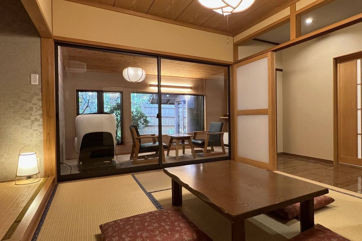 Una habitación tradicional japonesa con suelo de tatami, una mesa baja y puertas correderas.