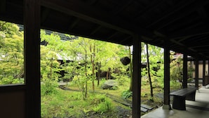 Un espacio al aire libre cubierto con vistas a un jardín, que incluye una estructura de madera, un banco y una maceta colgante.