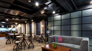 Ein modernes Interieur mit einem grauen Sofa, Holztischen und einem Fernseher an der Wand.