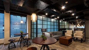 Ein modernes Interieur mit einem runden Holztisch, vier Hocker, einer Couch und zwei Sesseln.
