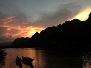 A boat docked at a harbor with mountains in the background. - Phong Nha Coco House (Bo Trach)