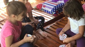 Three children sitting on a wooden bench, playing with small containers. - Phong Nha Coco House (Phong Nha)